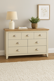 Cream bedroom dresser with 7 drawers, oak effect top, steel handles, from Lavish Kitchen Isle, shown in a realistic room setting.