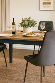 Baumhaus Signature Blue Dining Table with sleek wooden surface, set in a modern dining room with chairs and decorative lighting.