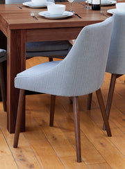 Pair of Baumhaus walnut light grey and grey dining chairs with wooden legs, shown from the side and front.