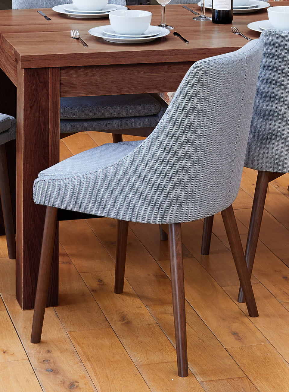 Pair of Baumhaus walnut light grey and grey dining chairs with wooden legs, shown from the side and front.