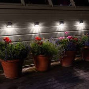 Lavish Kitchen Isle 18-pack solar-powered fence and wall LED outdoor lights illuminating a garden wall at dusk.