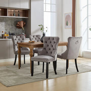 Set of four grey and beige velvet wingback dining chairs with button tufted backs and solid wood legs, stylish and comfortable for dining rooms.