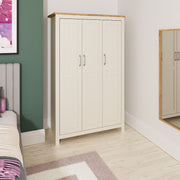 Cream and oak effect Ite 3-door wardrobe by Lavish Kitchen Isle with hanging rail, shelves, and storage drawers in a modern bedroom setting.